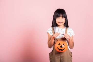 10 yaşında Asyalı bir çocuk elinde pembe arka planda izole edilmiş cadılar bayramı balkabağı, gülümseyen çocuk portresi Jack O balkabağı, Cadılar Bayramı tatili konsepti