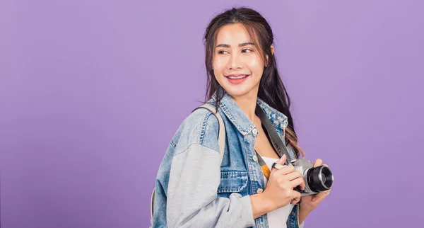 魅力的な肖像画幸せなアジアの美しい若い女性笑顔興奮した摩耗デニムやバッグを保持ヴィンテージ写真カメラ 女性旅行者女性写真家 スタジオ撮影紫色の背景に隔離 — ストック写真