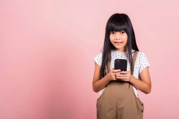 スタジオ撮影でSnsに携帯電話を使って楽しむアジアの子供10年ピンクの背景に孤立したスタジオショット スマートフォンを使った幸せな女の子のライフスタイル 友人とのチャットメッセージの入力 — ストック写真