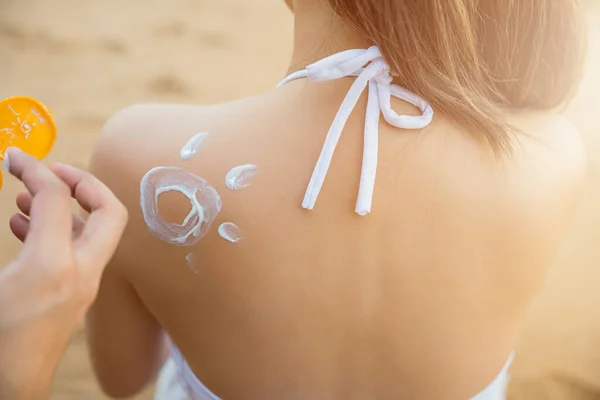 Happy young man applying suntan lotion with sun shape on girlfriend back shoulder at the beach, Asian man on beach applies sunscreen to the skin of woman