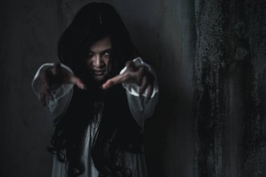 Korkunç hayalet kadın. Asyalı hayalet ya da zombi korkusunun yüzü ve gözü tüylü terk edilmiş eve uzanan karanlık oda, kadın makyajlı terör zombisi yüzü, mutlu Cadılar Bayramı konsepti.