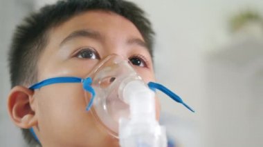 Asian Child using nebulizer mask equipment alone have smoke, Kid boy making makes inhalation nebulizer steam sick cough at home, oxygen spray inhaler therapy, stuffy nose and runny, Health medical