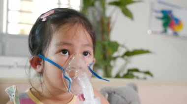 Kid girl making makes inhalation nebulizer steam sick cough at home, Asian Child using nebulizer mask equipment alone have smoke, stuffy nose and runny, oxygen spray inhaler therapy, Health medical