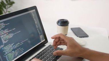 Web application development. programmer man writing program code sitting at workplace in office, software developer hands coding HTML programming with laptop computer, IT start up concept, back view