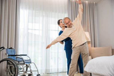 Old senior man enjoys training with physiotherapist for outstretched arms at home, Asian physical therapist patient nursing helping elderly exercising arm stretch, Rehabilitation of disabled concept