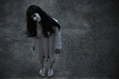 Kadın hayalet korkusu binanın altında duruyor yukarı bakıyor, cadılar bayramı konseptine bakıyor.