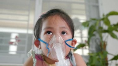 Kid girl making makes inhalation nebulizer steam sick cough at home, Asian Child using nebulizer mask equipment alone have smoke, stuffy nose and runny, oxygen spray inhaler therapy, Health medical