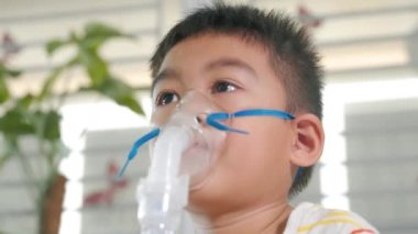 Asian Child using nebulizer mask equipment alone have smoke, Kid boy making makes inhalation nebulizer steam sick cough at home, oxygen spray inhaler therapy, stuffy nose and runny, Health medical