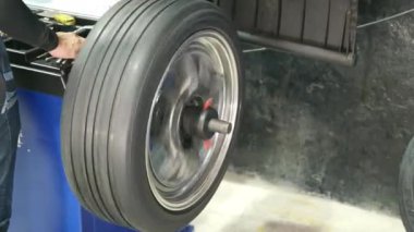 Auto mechanic balancing wheel places weights on steel rim with machine balancer at car service, Seasonal tire change fixing problems replacing broken parts