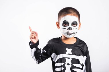 Halloween Kid. Child man horror face painting make up for ghost scary point finger to side space, Portrait of little boy wearing skeleton costume isolated white background, Happy halloween day concept