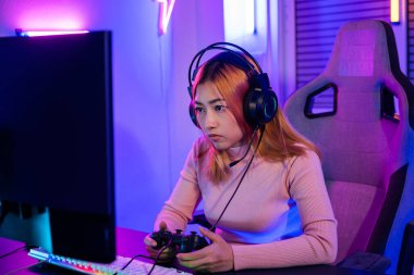 You win. Gamer using joystick controller plays online video game with computer neon lights she winning, woman wear gaming headphones playing live stream esports games console at home celebrating win