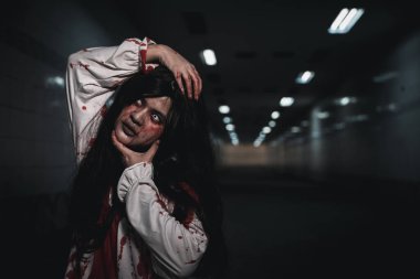 Happy halloween day concept. Screaming zombie female face with blood grabs her head to twist it off, Horror bloodthirsty woman ghost or zombie she is horror scary with breaks her neck at dark night