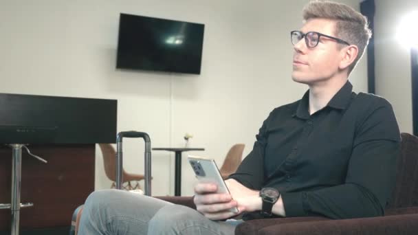 Νεαρός Όμορφος Επιχειρηματίας Αποσκευές Που Κάθεται Στο Lounge Play Smartphone — Αρχείο Βίντεο