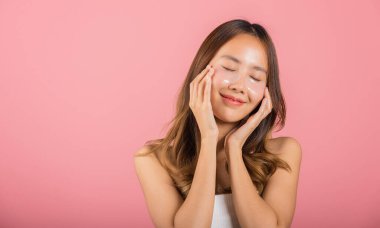 Anti aging. Asian beautiful young woman smiling mask cosmetic patches gel under the eyes, Portrait female applying medical hydrogel eye patch on face, studio shot isolated on pink background, skincare