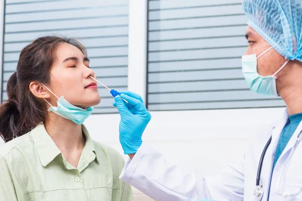 Coronavirus test, Doctor man take saliva sample through nose with cotton swab to check coronavirus test from Asian young woman, Covid-19 pandemic outbreak Medicine And Health Care Concept