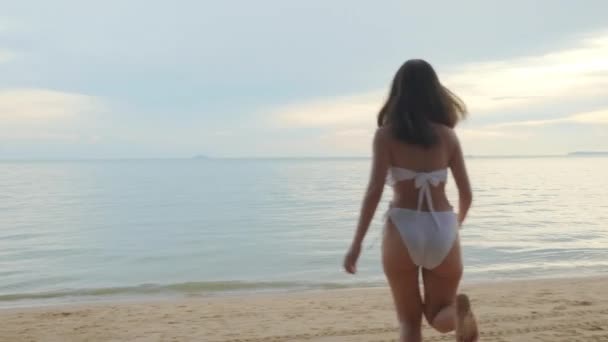 回头看 穿着比基尼泳衣的年轻貌美的女人跑到热带沙滩上喝水 快乐的亚洲女人在外面度假 暑假的概念 — 图库视频影像