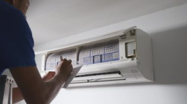 Professional technician male with clipboard checking operation of air conditioner, The man looking at air condition for installation quote indoors of the bedroom, worker to service cleaning and repair