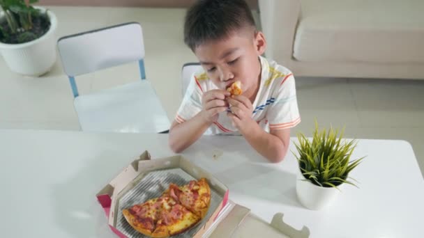 Ευτυχισμένο Ασιατικό Αγοράκι Χρόνια Κάθεται Τρώει Τεράστια Πίτσα Στο Τραπέζι — Αρχείο Βίντεο