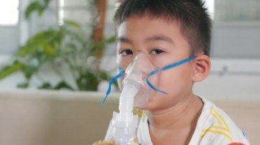 Asian Child using nebulizer mask equipment alone have smoke, Kid boy making makes inhalation nebulizer steam sick cough at home, oxygen spray inhaler therapy, stuffy nose and runny, Health medical