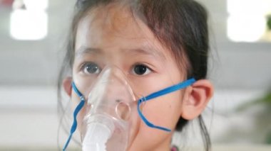 Kid girl making makes inhalation nebulizer steam sick cough at home, Asian Child using nebulizer mask equipment alone have smoke, stuffy nose and runny, oxygen spray inhaler therapy, Health medical