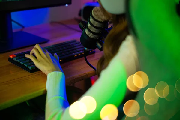 Asian young gamer woman press on keyboard to playing video games online on computer she live stream and chat with fans, Streamer female talking with microphone in gaming room, game streaming concept