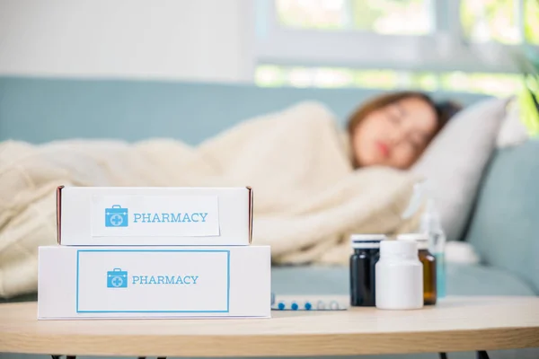 Asian beautiful female use pharmacy first aid kit box delivery service from hospital, Young woman tired sick she sleep and resting on sofa after take medicines pills in living room at home, healthcare
