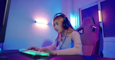 Kazanmak. Oyun kulaklığı takan, video oyunu oynayan genç bir kadın Neon Room 'da heyecanlanıyor, Happy Gamer' ın gençliği online video oyunları oynuyor elini kaldırıp turnuvayı kazanıyor, E-Sport