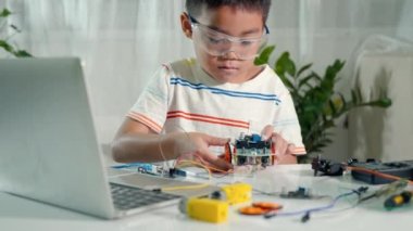 Küçük çocuk oyuncakları birleştirmeye çalışıyor, Asyalı çocuk Arduino robot araba ödevinde tekerlek birleştiriyor, elektronik yapay zeka atölyesi çevrimiçi okul dersi yaratıyor.