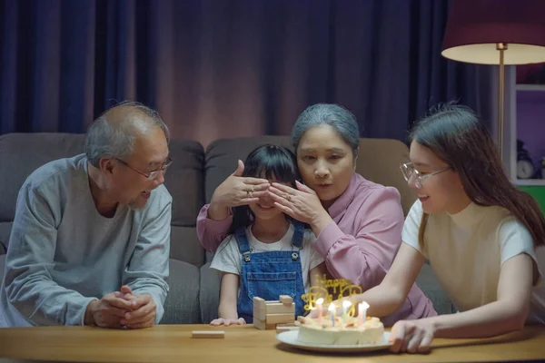 誕生日サプライズコンセプト 幸せなアジアの家族の祖父母と母親は 夜の時間に家でろうそくを吹いて孫娘のケーキと一緒に誕生日の歌のパーティーを楽しむ — ストック写真