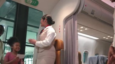 Asyalı uçuş görevlileri, yolcuları uçakla karşılarken ve uçağa binerken, mutlu hostesler veya hostesler seyahat sırasında yolcu biletlerini kontrol ederken selamlıyorlar.