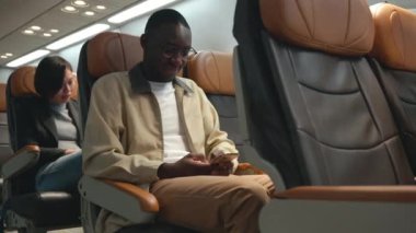 Uçakta cep telefonu test kablosuz bağlantısını kullanan işadamı, akıllı telefon yazan siyah adam iş seyahati sırasında sosyal ve haber okudu