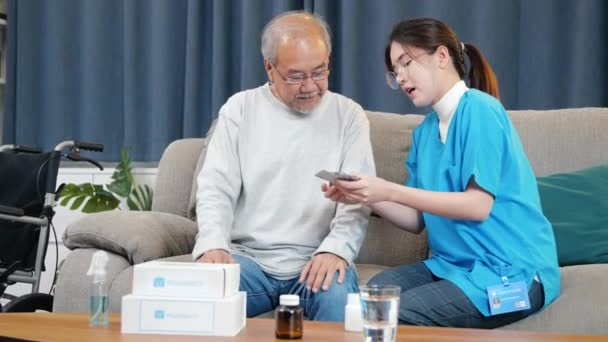 Asiatische Krankenschwester Mit Arzt Erklärt Aufmerksamen Älteren Mann Hause Verschreibungspflichtige — Stockvideo