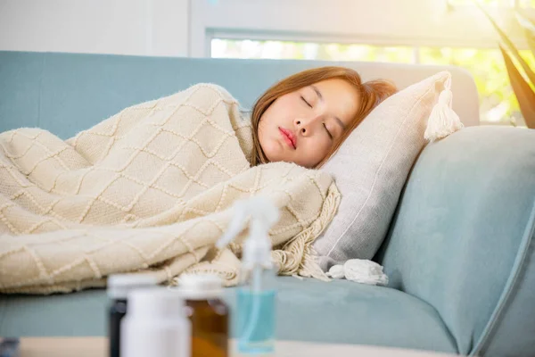 Asian young woman tired sick she sleep and resting on sofa after take medicines pills in living room at home, beautiful female use pharmacy first aid kit box delivery service from hospital, healthcare