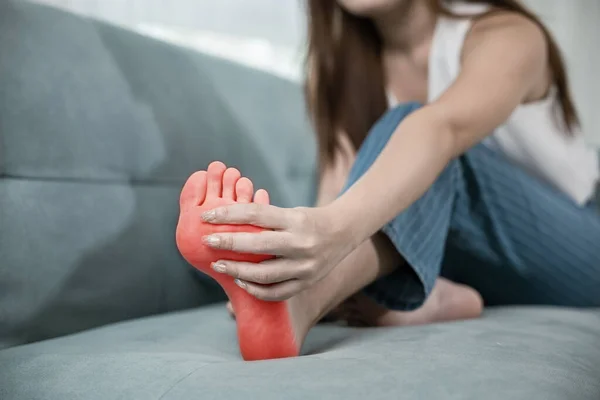 Asiática Jovem Mulher Sentada Sofá Segurando Pés Músculos Alongados Têm — Fotografia de Stock