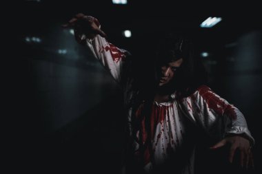 Bloody halloween makeup. Horror bloodthirsty ghost girl hair covering face and eye reach arm out, Asian woman zombie with blood she death and scary at night in tunnel, Happy halloween day concept