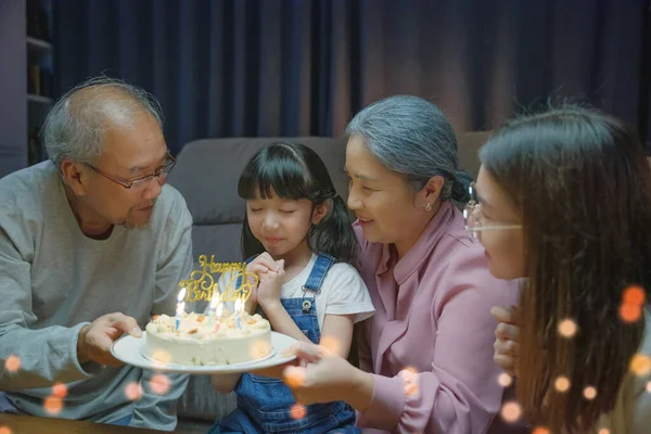 幸せなアジアの家族の祖父母と母は 夜に家でろうそくを吹いて孫娘のケーキと誕生日の歌のパーティーを楽しむ 誕生日の驚きのコンセプト — ストック写真