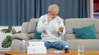 Asyalı endişeli son sınıf öğrencisi oturma odasında ilaç alıyor, yaşlı adam bitkisel kendini iyileştiriyor eczaneden RX hapı alıyor, ev hapları, sağlık hizmetleri...