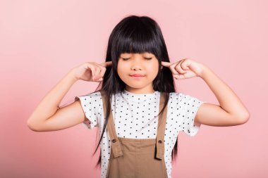 Asyalı küçük çocuk 10 yaşında. Stüdyoda kulaklarını ve gözlerini kapat. Pembe arka planda izole bir şekilde çek.
