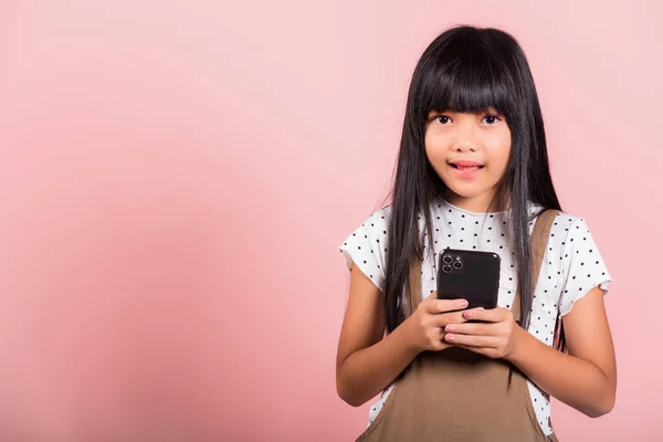 スタジオ撮影でSnsに携帯電話を使って楽しむアジアの子供10年ピンクの背景に孤立したスタジオショット スマートフォンを使った幸せな女の子のライフスタイル 友人とのチャットメッセージの入力 — ストック写真