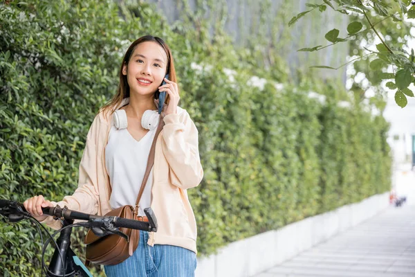 아시아의 자전거를 야외를 있습니다 그녀는 친구와 휴대폰 통화를 있습니다 여성은 — 스톡 사진