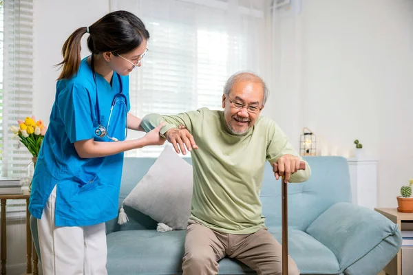 国际老年人日 年轻妇女帮助支持骨科患者在家里用手杖站起来 护士长帮助支持老年残疾人用手杖站起来 — 图库照片
