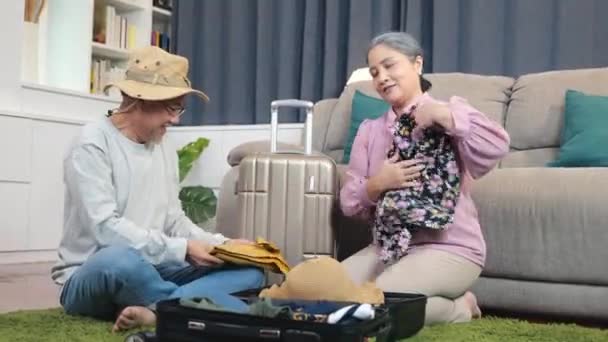 亚洲夫妇老年结婚退休准备行李行李箱安排旅行 浪漫的退休夫妇包装衣服旅行袋行李箱一起在家里的客厅地板上 — 图库视频影像