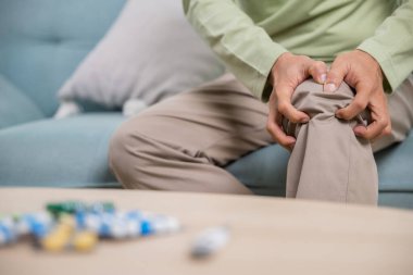 Yaşlılık. Asyalı son sınıf öğrencisi emeklilik eklem ağrısı koltukta oturan yaşlı adam el ele tutuşan yaşlı adam, dedelerin sağlık sorunları evde.