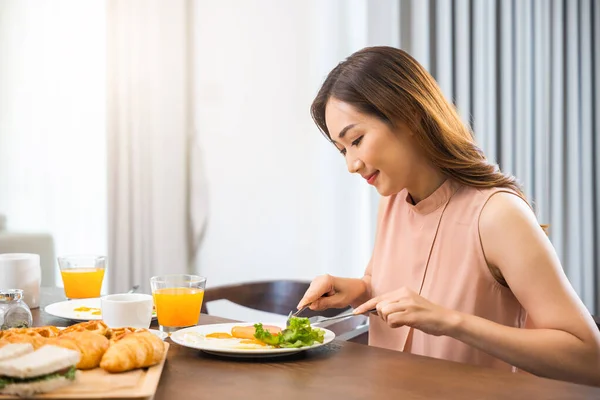 亚洲女青年坐在厨房桌子上吃着健康的早餐 女青年吃着新鲜的早餐和饮料 然后在早上回家工作 — 图库照片