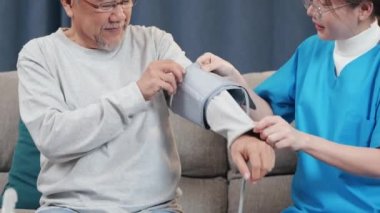 Asian nurse visit patient senior man at home she measuring arterial blood pressure on arm in living room, Doctor woman examine do checking old man client heart rate with pulsimeter monitor, Healthcare