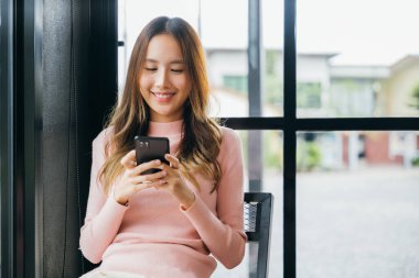 Akıllı telefon cihazında mesaj yazan güzel bir kadın ve sosyal medya ile eğlenceli bir yaşam tarzı, kafede cep telefonu kullanan Asyalı genç bir kadın ve internetten alışveriş yapan bir kadın.