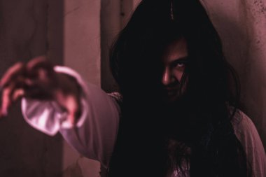 Korkunç hayalet kadın. Asyalı hayalet ya da zombi korkusunun yüzü ve gözü tüylü terk edilmiş eve uzanan karanlık oda, kadın makyajlı terör zombisi yüzü, mutlu Cadılar Bayramı konsepti.