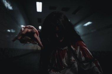 Bloody halloween makeup. Asian woman zombie with blood she death and scary at dark night in tunnel, Horror bloodthirsty ghost girl hair covering face and eye reach arm out, Happy halloween day concept