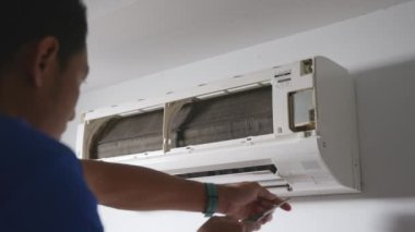 Teknisyen erkek klimayı söker ve yıkama için hazırlar, temizler ve yıkar, temizlik ve onarım için çalışır, sağlıklı yaşam için toz ve kir.