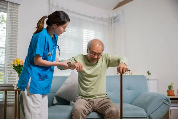 国际老年人日 关爱护士帮助支持老年残疾人用手杖站起来 年轻妇女帮助支持骨科患者在家里用手杖站起来 — 图库照片